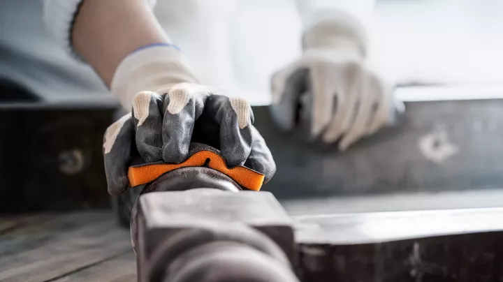 Una persona que usa equipo de seguridad agarra un tubo de metal para alinearlo.