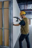 Trabajador perforando panel de pared.