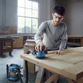 Una persona que usa equipo de seguridad lija una puerta de madera con una lijadora orbital conectada.