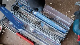 Una persona que lleva puesto el equipo de seguridad selecciona una hoja de sierra de un estuche de hojas organizado.