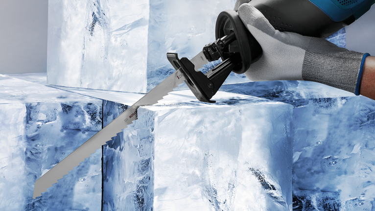 Una persona que usa equipo de seguridad utiliza una sierra alternativa para cortar grandes bloques de hielo.