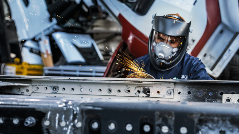 Una persona que usa equipo de seguridad muele metal, creando chispas brillantes.