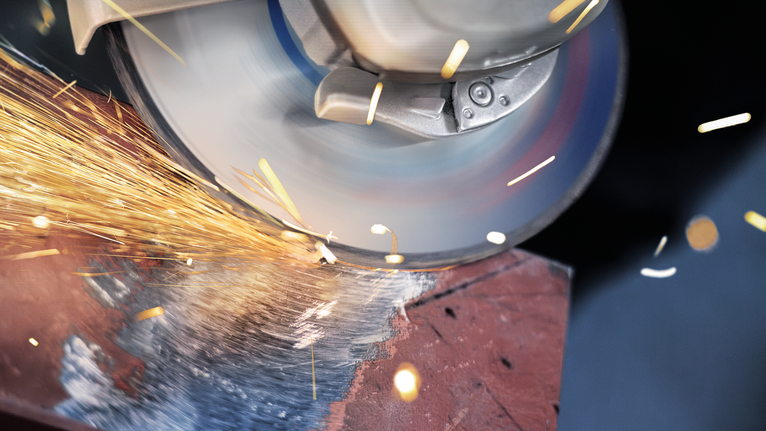 Amoladora angular cortando metal, produciendo chispas brillantes.