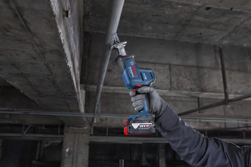 Una persona que usa equipo de seguridad corta un tubo de metal con una sierra alternativa.