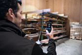 Una persona utiliza un termohigrómetro para medir la temperatura y la humedad en un área de almacenamiento de madera.