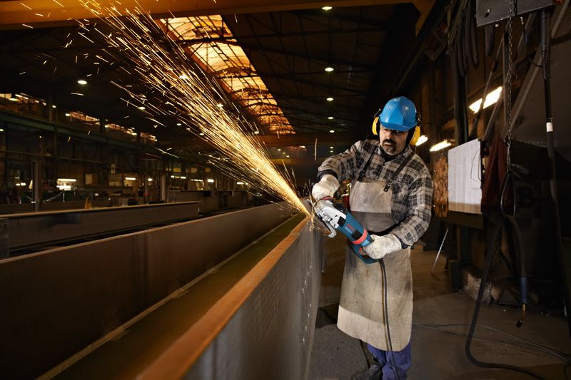 Turvavarustust kandev inimene lihvib suure nurklihvijaga terastala.