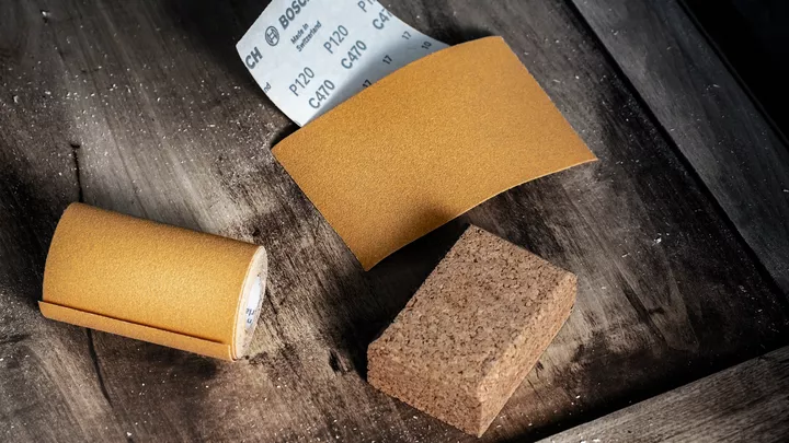 Liivapaberi rullid ja lehed lihvimisplokiga puitpinnal.