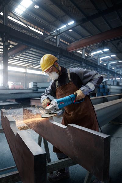 Turvavarustust kandev inimene lihvib suurt metalltala, tekitades sädemeid.