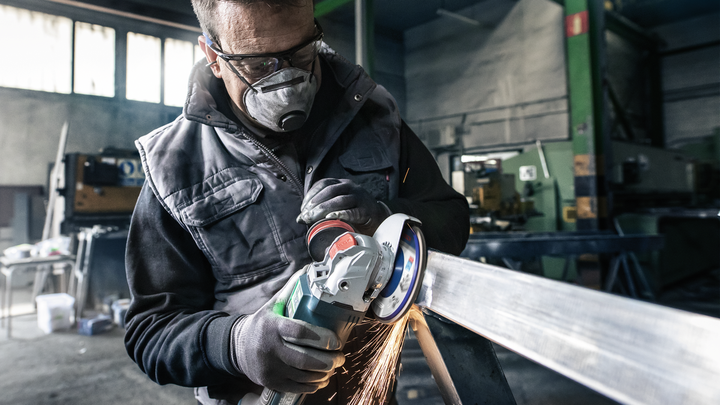 Kaitsevarustust kandev inimene lihvib metalltala, tekitades sädemeid.