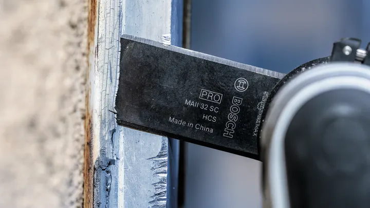 Võnkuv tööriistatera lõikab värvitud puitraami.