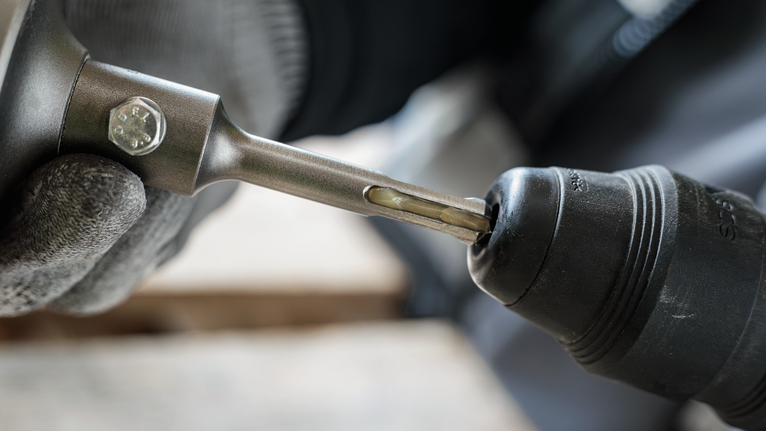 Turvavarustust kandev inimene sisestab puuritera elektritööriista.