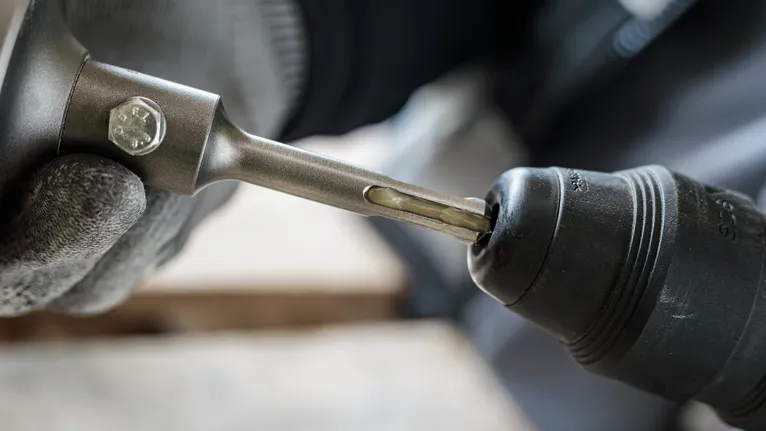 Turvavarustust kandev inimene sisestab puuritera elektritööriista.