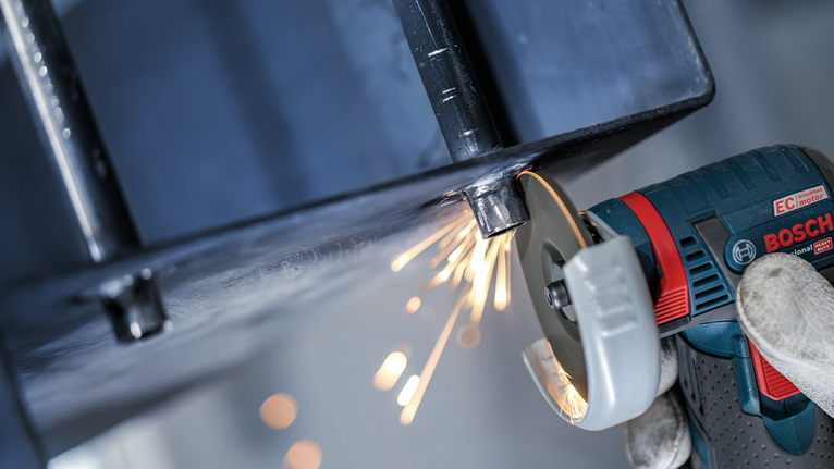 Turvavarustust kandev inimene lihvib metalltala, tekitades sädemeid.