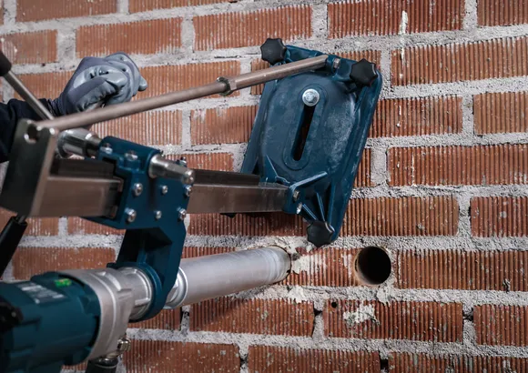 Turvavarustust kandev inimene puurib telliskiviseina täpse augu.