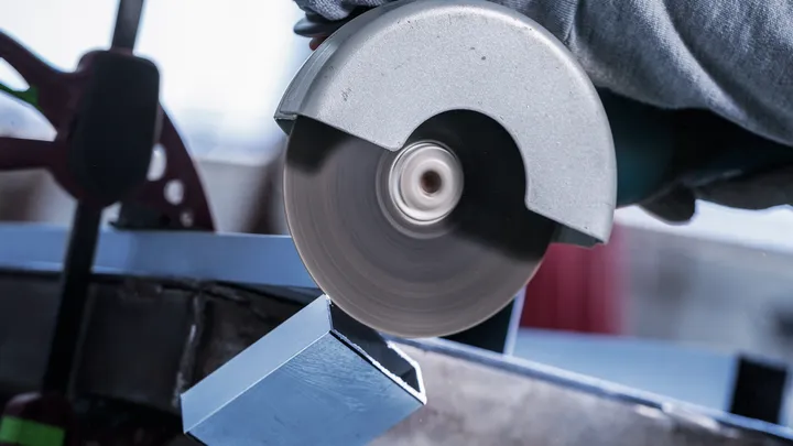 Turvavarustust kandev töötaja lõikab metalltala ketassaagiga.