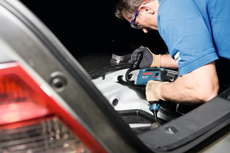 Turvavarustust kandev inimene kasutab auto pakiruumis löökpuurit.