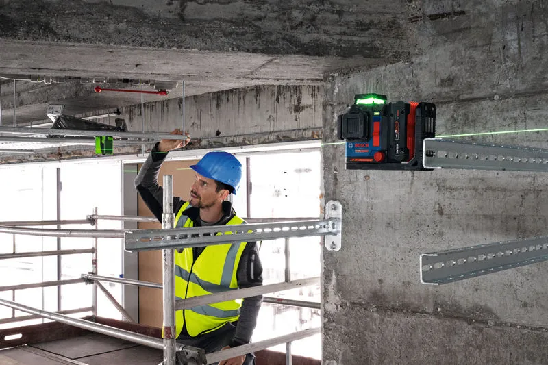 Turvavarustust kandev inimene joondab laseriga nivelleerimisvahendi abil metallrööpaid.