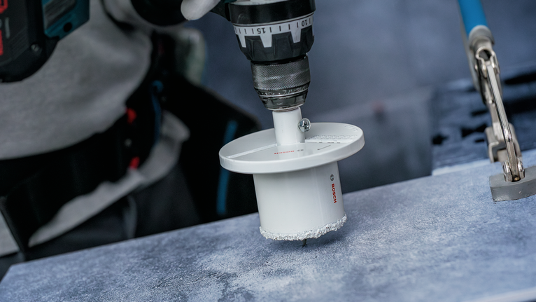 Turvavarustust kandev inimene puurib plaaditud pinnale suure augu.