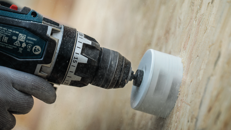 Turvavarustust kandev inimene puurib augusae otsakuga puitu augu.