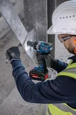 Turvavarustust kandev inimene kasutab metalltalal akutoitel löökkruvikeerajat.