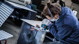 Turvavarustust kandev inimene kasutab metalli lihvimiseks elektrilist tööriista.