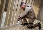 Turvavarustust kandev inimene kasutab puitkarkassil akutoitel lööktrelli.