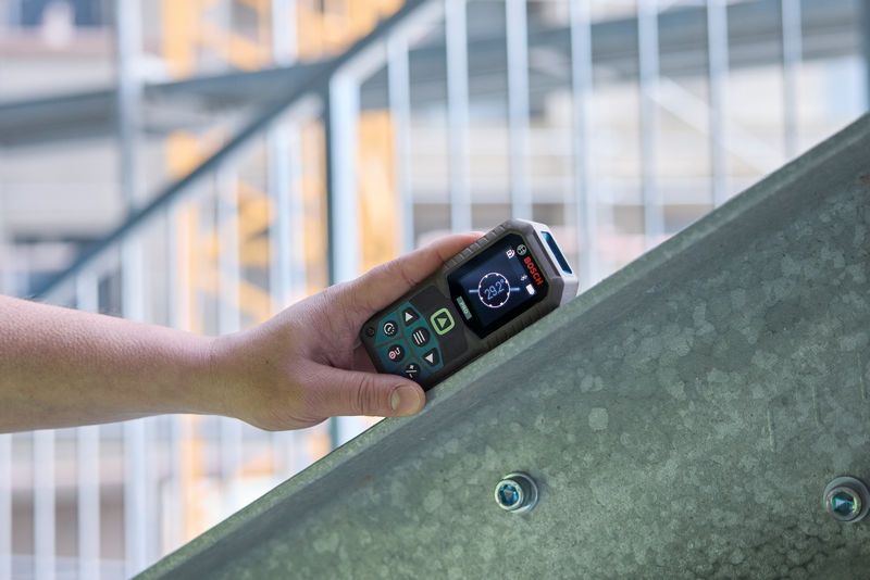 Inimene kasutab lasermõõtjat metallkiirel.