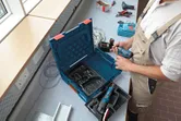 Turvavarustust kandev inimene valmistab tööjaamas ette akupuurit.