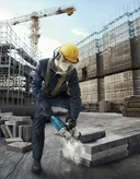 A person wearing safety equipment cuts concrete blocks on a construction site.