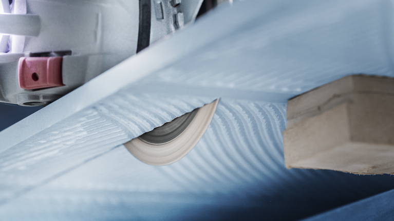 Circular saw blade cutting through a sheet of material supported by a wooden block.