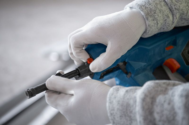Person wearing safety equipment adjusts a cordless concrete nailer.