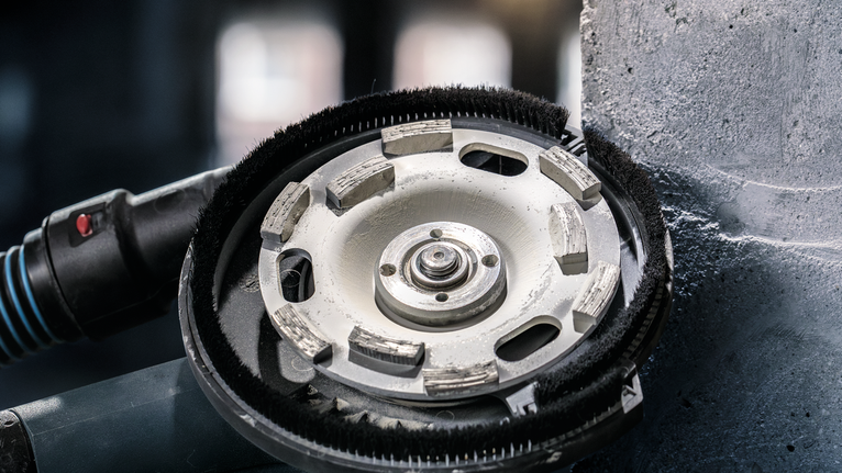 Diamond cup wheel grinder smooths concrete on a vertical surface.