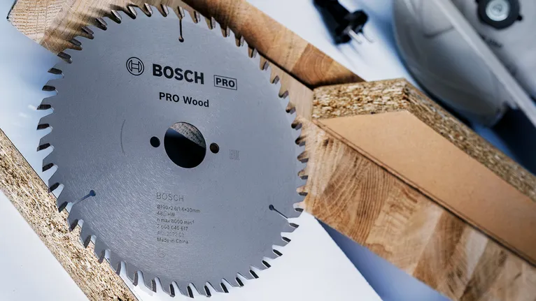 Circular saw blade placed beside wooden planks on a work surface.
