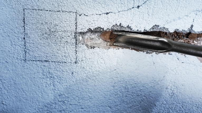 Chisel tool creating a groove in a concrete wall.