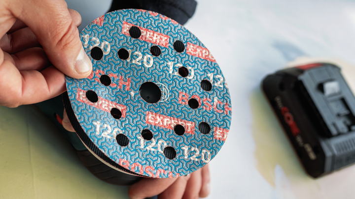 Person attaches sanding disc to a power sander.