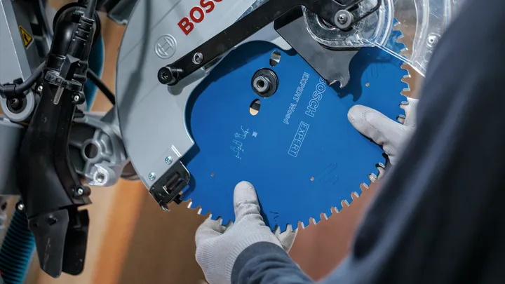 Person wearing safety equipment installs a circular saw blade.