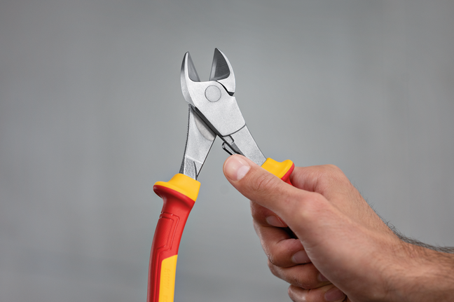 Person holding insulated wire cutters.