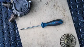Flathead screwdriver placed on a wooden surface beside metal fittings.