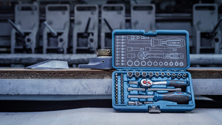 Socket and screwdriver set with multiple bits arranged in a blue case on a workbench.