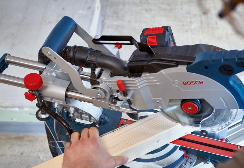 Una persona utiliza una sierra ingletadora inalámbrica para cortar una tabla de madera.