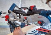 Una persona utiliza una sierra ingletadora inalámbrica para cortar una tabla de madera.