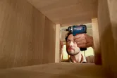 Una persona utiliza un taladro inalámbrico para ensamblar un gabinete de madera.