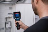 Una persona utiliza una cámara térmica para inspeccionar un panel eléctrico.