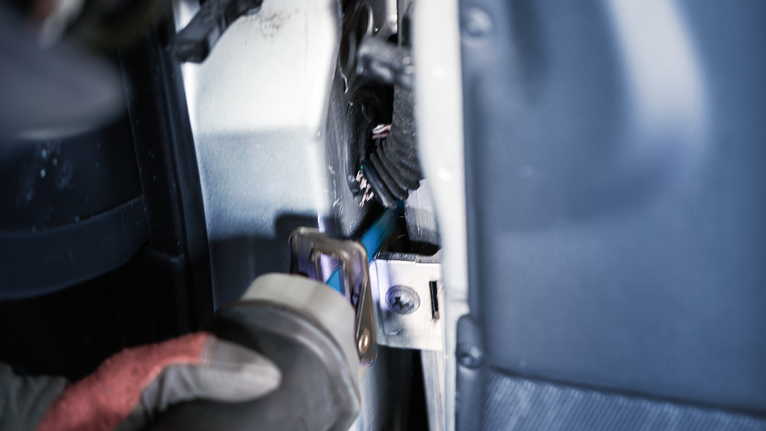 Una persona que usa equipo de seguridad utiliza una herramienta eléctrica para cortar el marco de la ventana de un automóvil.