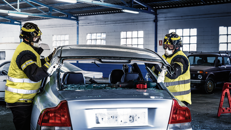 Una persona que usa equipo de seguridad corta el techo de un automóvil utilizando una sierra alternativa.