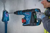Una persona que usa equipo de seguridad perfora hormigón con un martillo perforador inalámbrico.