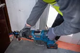 Una persona que usa equipo de seguridad corta metal utilizando una sierra alternativa inalámbrica.