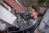 Una persona que usa equipo de seguridad usa una sierra alternativa para cortar madera del techo al aire libre.
