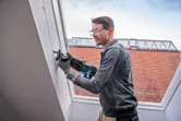 Una persona que usa equipo de seguridad corta una pared con una sierra alternativa.