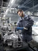 Una persona que usa equipo de seguridad utiliza una herramienta eléctrica para ensamblar maquinaria en una fábrica.